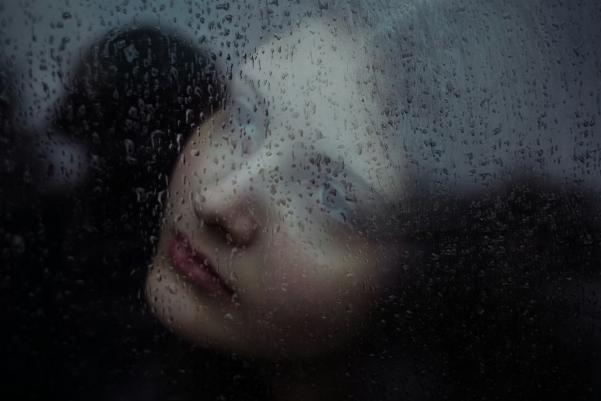 Portrait through rain-streaked glass
